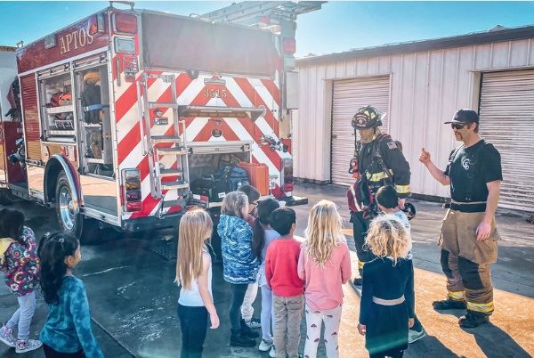 Young students learning fire safety from two Firefighters outside the Fire Station.