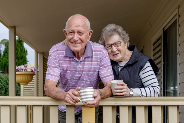 Two senior citizens on a porch smiling